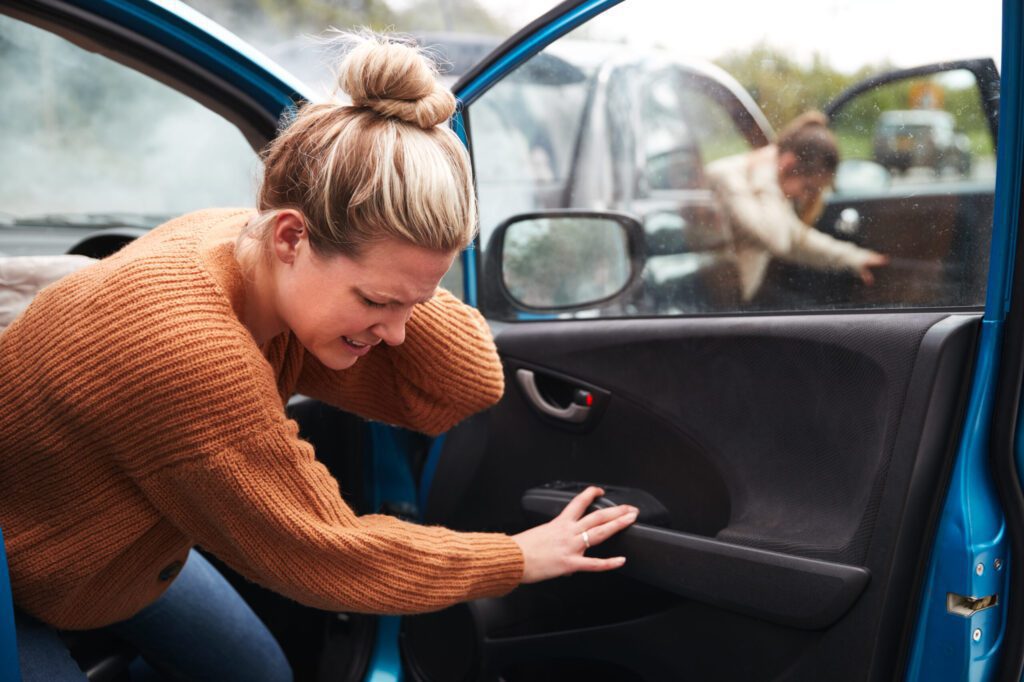 injured passenger holding neck while exiting car after a serious head on accident