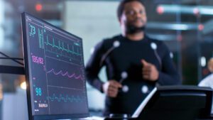Athlete running on treadmill with sensors detecting vitals, shown on monitor
