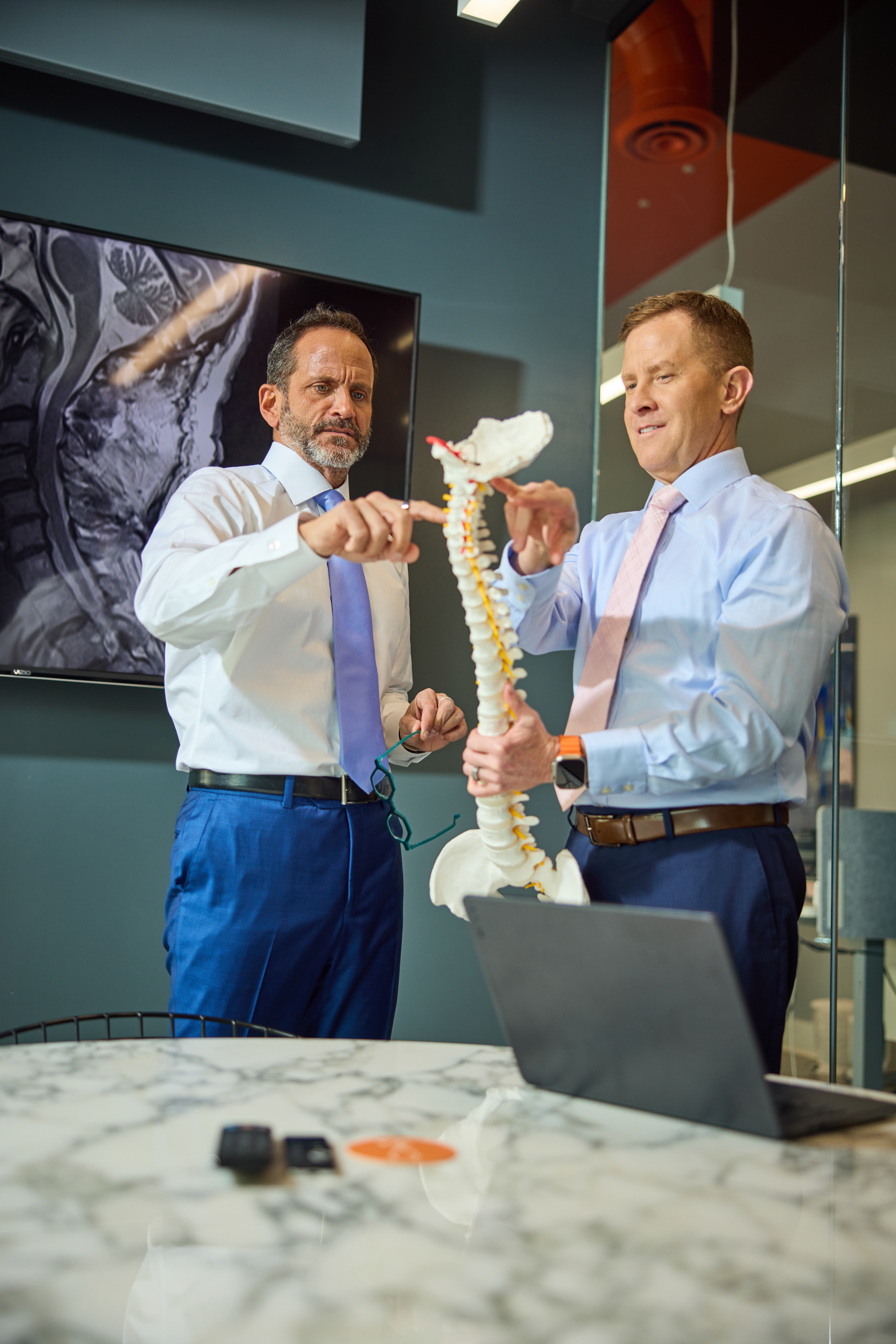 Joe Zarzaur and Dr. Evan Malone examining a demonstration spinal column to determine where an injury occurred in client